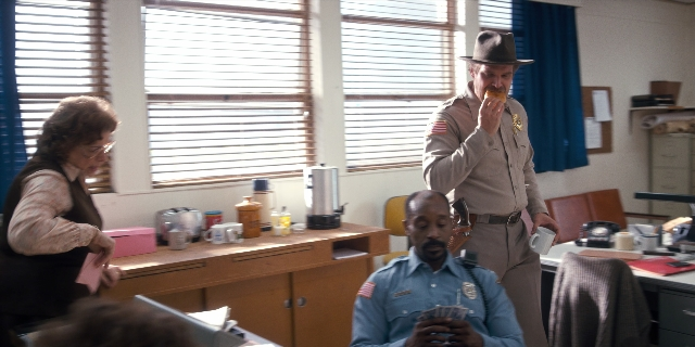 Wide shot frame from Stranger Things — desk, standing, table
