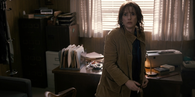 Wide shot frame from Stranger Things — standing, room, coat