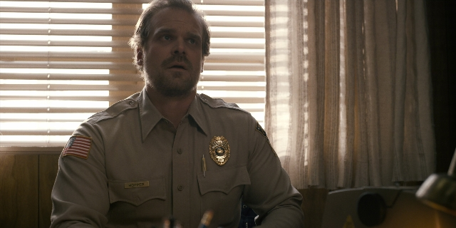Wide shot frame from Stranger Things — sitting, uniform, shirt