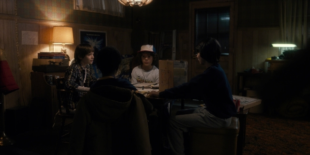 Wide shot frame from Stranger Things — sitting, standing, room