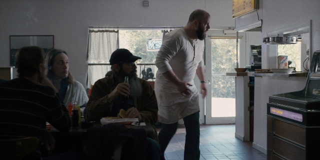 Wide shot frame from Stranger Things — sitting, standing, table