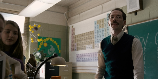 Wide shot frame from Stranger Things — sitting, standing, tie