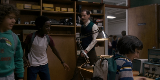 Wide shot frame from Stranger Things — standing, door, face