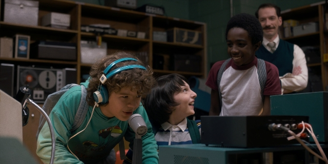 Wide shot frame from Stranger Things — standing, dialogue, beard