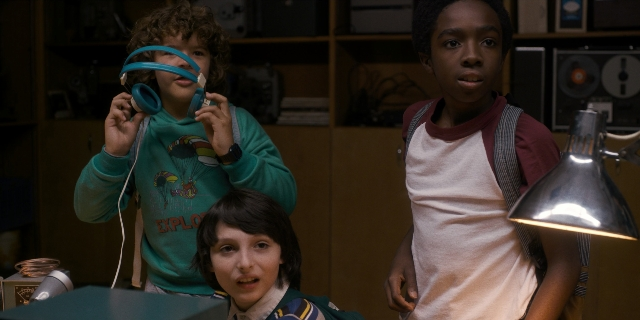 Wide shot frame from Stranger Things — standing, room, shirt
