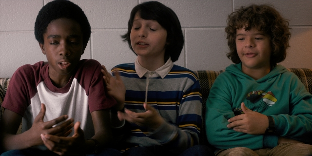 Wide shot frame from Stranger Things — sitting, dialogue, phone