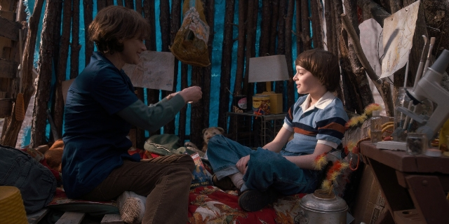 Wide shot frame from Stranger Things — sitting, room, bed