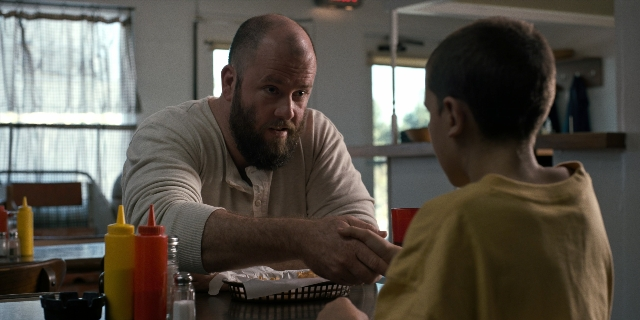 Wide shot frame from Stranger Things — sitting, table, dialogue
