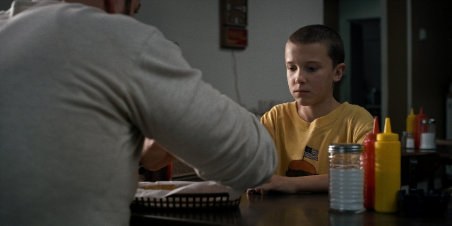 Wide shot frame from Stranger Things — sitting, standing, kitchen