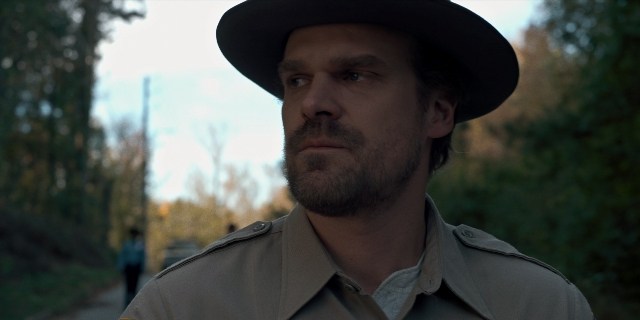Medium shot frame from Stranger Things — hat, coat, beard