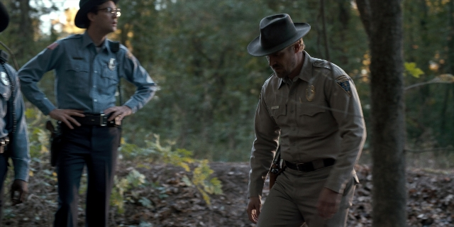 Wide shot frame from Stranger Things — walking, dialogue, hat