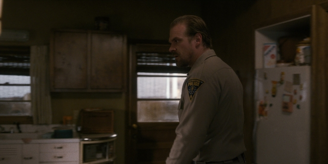 Wide shot frame from Stranger Things — standing, kitchen, refrigerator