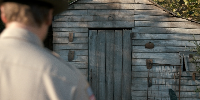 Wide shot frame from Stranger Things — standing, door, hat