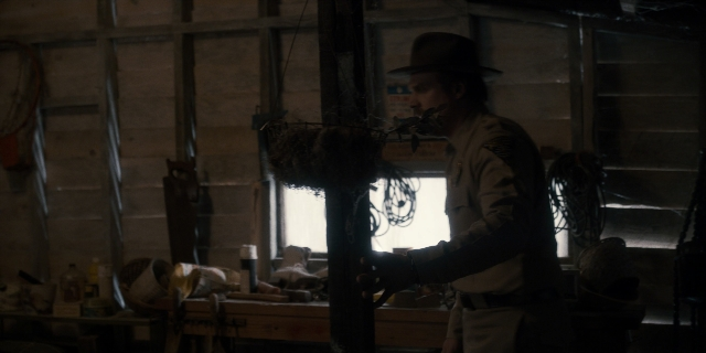 Wide shot frame from Stranger Things — standing, hat, hand