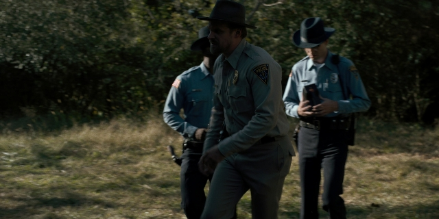 Wide shot frame from Stranger Things — walking, hat, uniform
