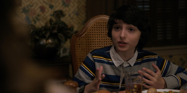 Medium shot frame from Stranger Things — sitting, plate, room