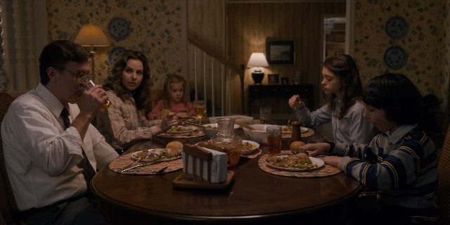 Wide shot frame from Stranger Things — sitting, room, table