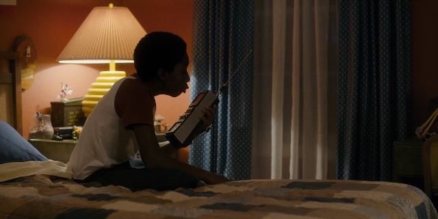 Wide shot frame from Stranger Things — sitting, room, bed