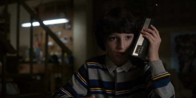 Wide shot frame from Stranger Things — standing, room, phone
