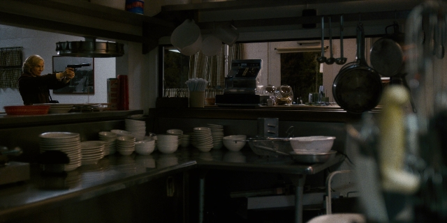 Wide shot frame from Stranger Things — table, kitchen, gun