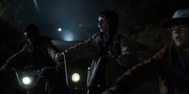Wide shot frame from Stranger Things — street, hat, night