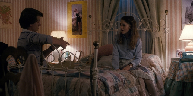 Wide shot frame from Stranger Things — sitting, room, bed