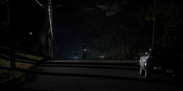 Wide shot frame from Stranger Things — standing, street, hat