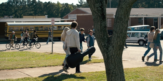 Wide shot frame from Stranger Things — walking, street, bicycle