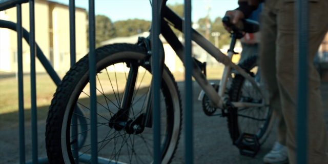 Wide shot frame from Stranger Things — hand, bicycle, person