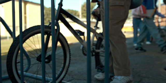 Wide shot frame from Stranger Things — standing, walking, bicycle