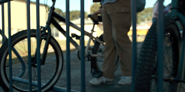 Wide shot frame from Stranger Things — standing, street, bicycle