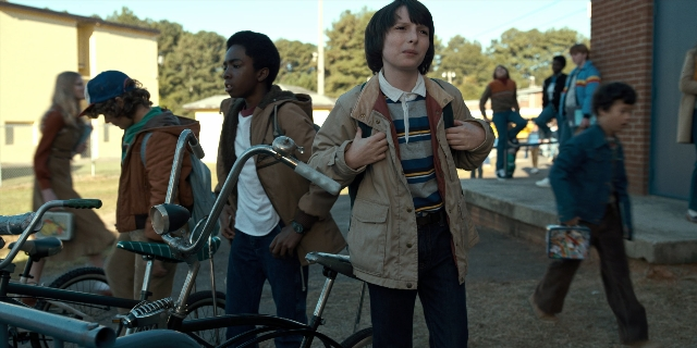 Wide shot frame from Stranger Things — standing, walking, phone