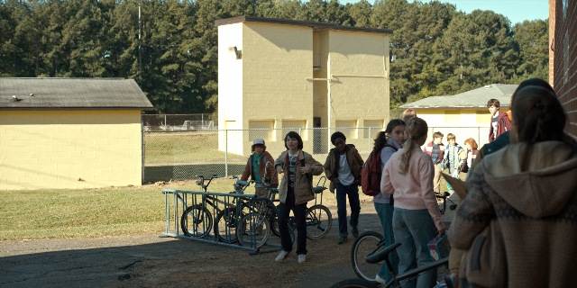 Wide shot frame from Stranger Things — standing, dialogue, house