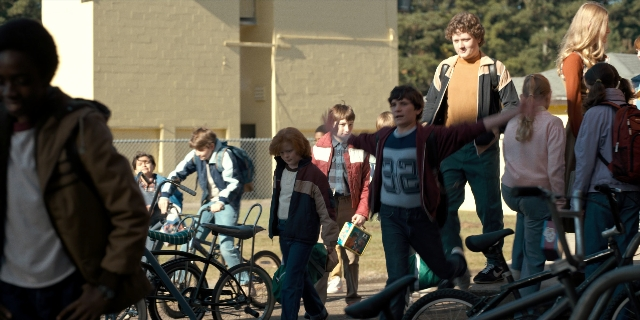 Wide shot frame from Stranger Things — walking, street, bicycle