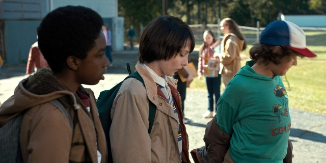 Wide shot frame from Stranger Things — standing, walking, hat