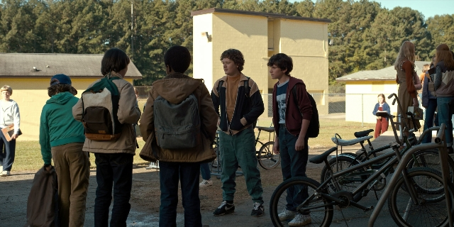 Wide shot frame from Stranger Things — standing, dialogue, bicycle