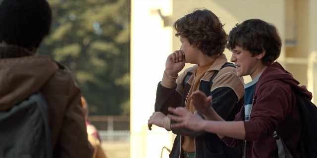 Wide shot frame from Stranger Things — standing, dialogue, hand