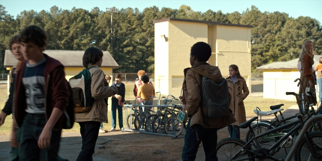 Wide shot frame from Stranger Things — walking, bicycle, jacket