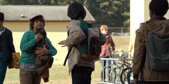 Wide shot frame from Stranger Things — standing, dialogue, hat