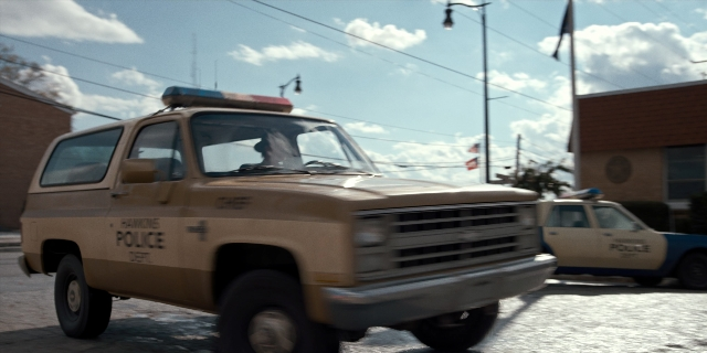 Wide shot frame from Stranger Things — street, car, wheel