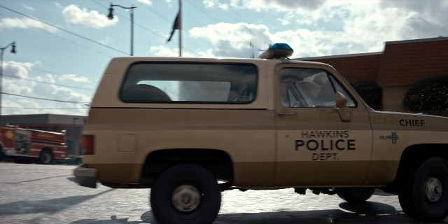 Wide shot frame from Stranger Things — street, hat, uniform