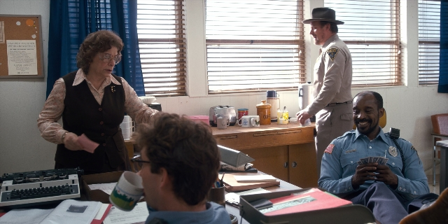 Wide shot frame from Stranger Things — sitting, desk, standing