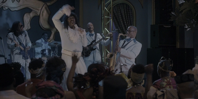 Wide shot frame from Coming 2 America — standing, beard, hair