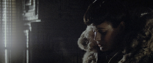 Wide shot frame from Blade Runner — room, hat, coat