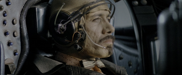 Wide shot frame from Blade Runner — room, hat, mustache