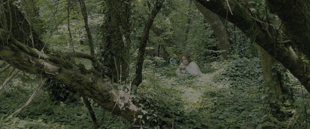 Wide shot frame from Blade Runner 2049 — sitting, dress, forest