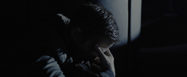 Wide shot frame from Blade Runner 2049 — sitting, room, face