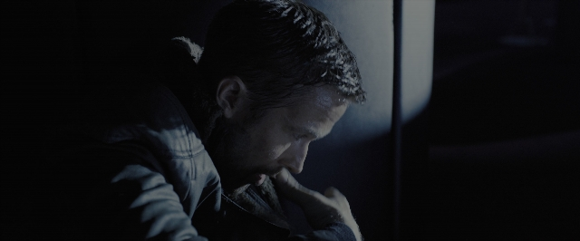Wide shot frame from Blade Runner 2049 — sitting, room, hand