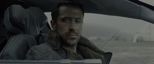 Medium shot frame from Blade Runner 2049 — sitting, car, beard