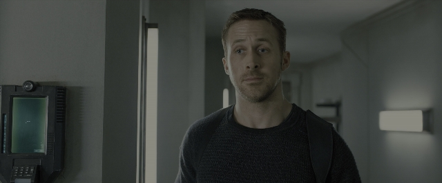 Medium shot frame from Blade Runner 2049 — standing, phone, door